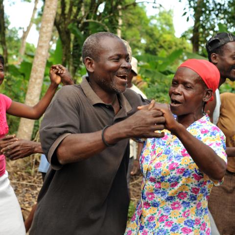 Photo showing five people dancing outside, with smiles on their faces.