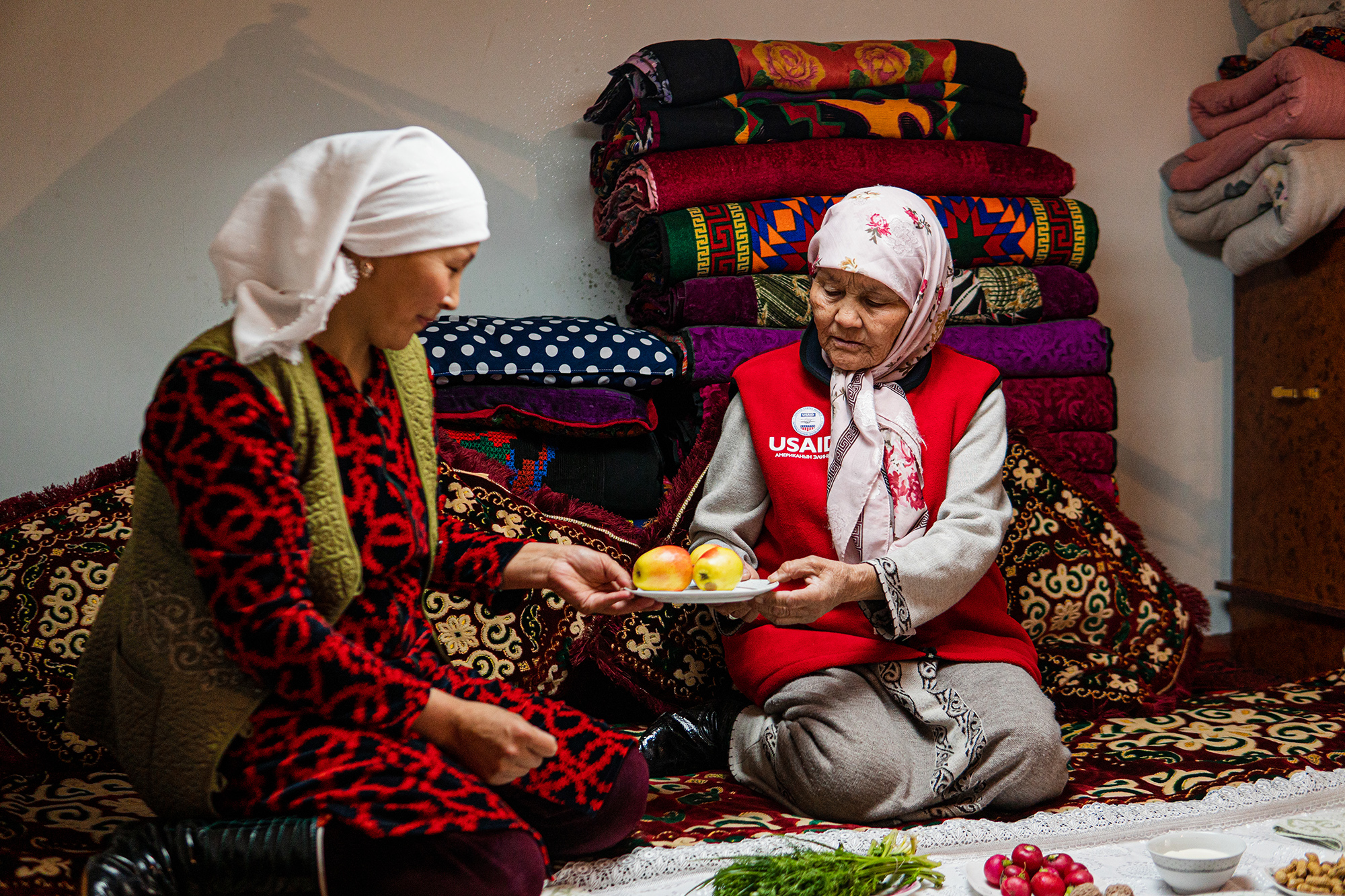 Two women kneeling, sharing a meal