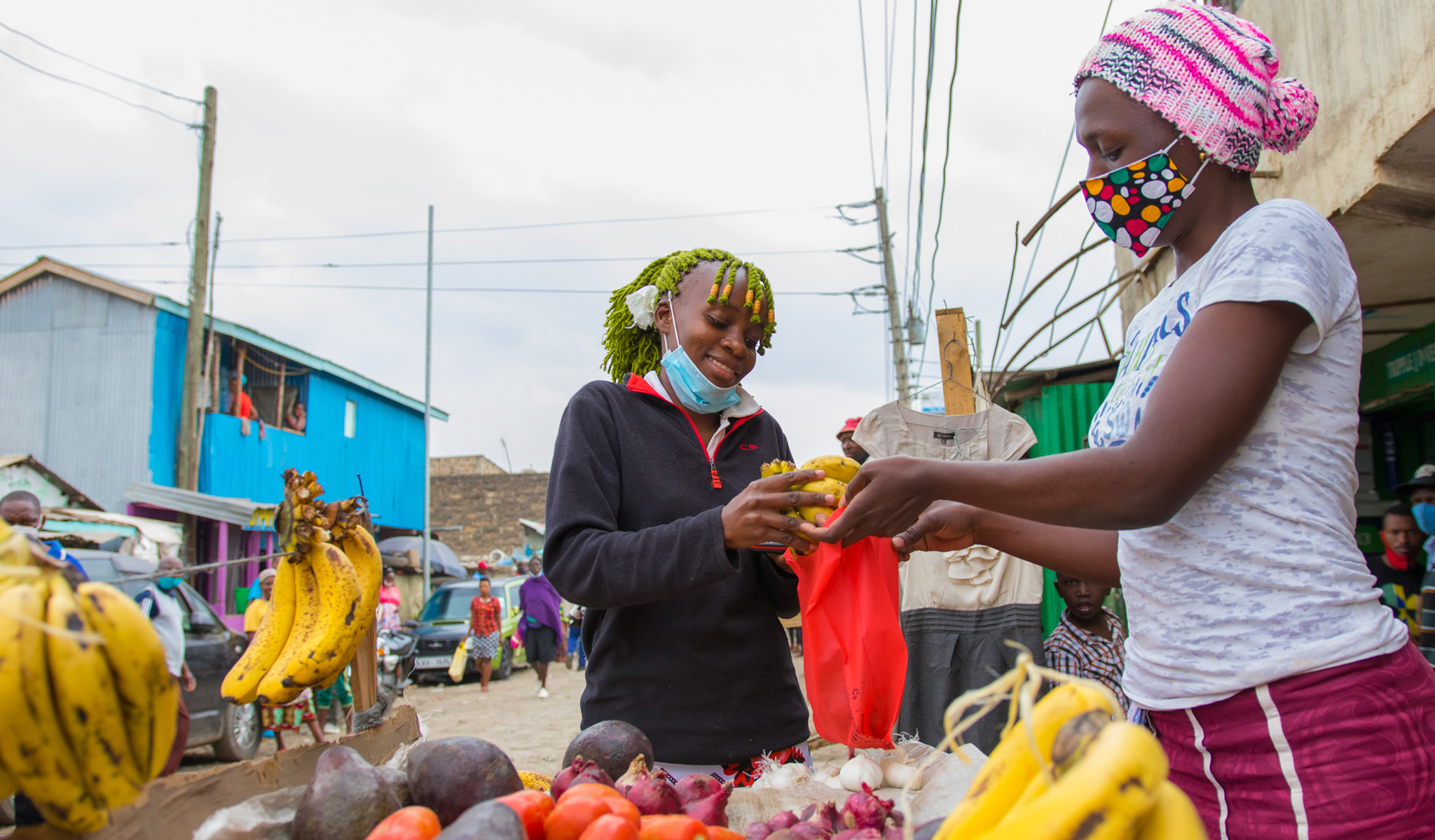 Photo of "Cash Transfer Beneficiary" Ann Mueni, 20, purchasing fruits and vegetables for her household using the Kes 4000 received through mobile money transfer.