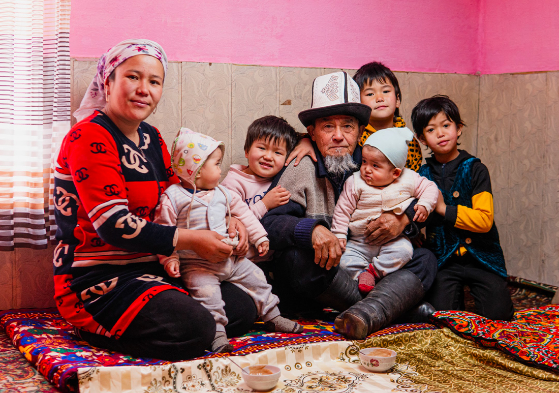 Family photo of two adults and five young children of various ages in traditional garb.