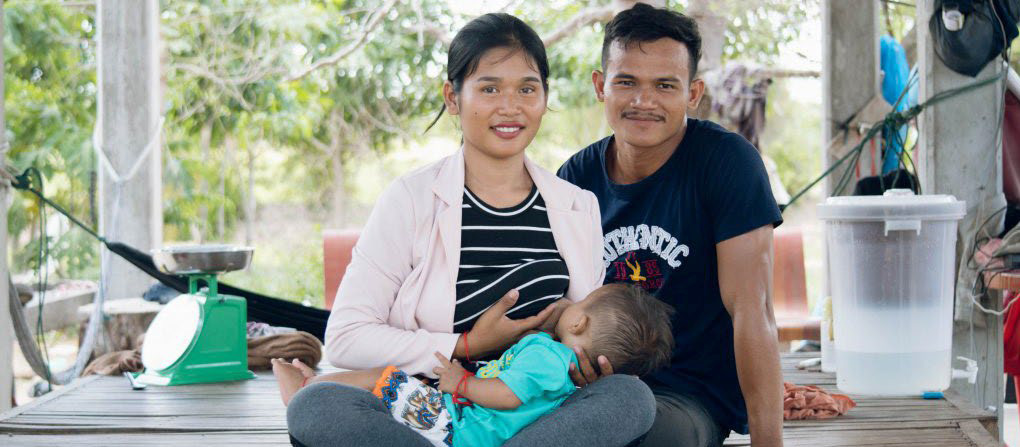 Photo of a woman breastfeeding with a man sitting next to her