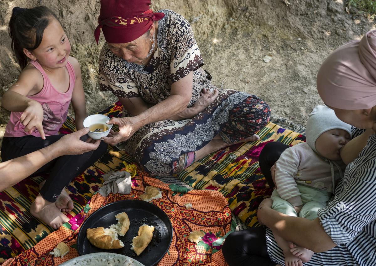 family sharing a meal while mother breastfeeds child