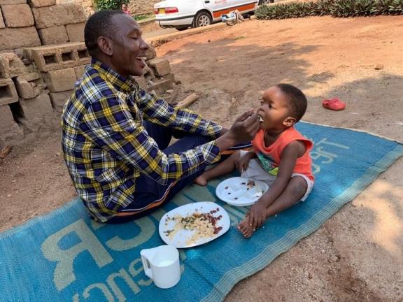A father smiles while feeding his son.
