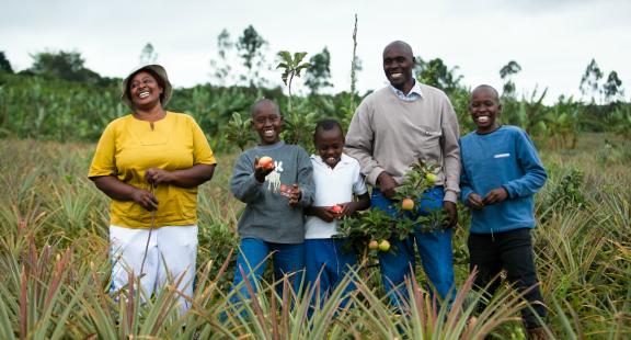 Farming Family in Uganda smiling in a group photo with their crop