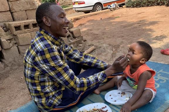 A father smiles while feeding his son