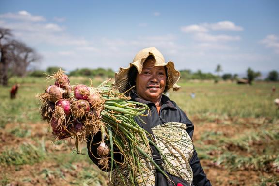 Smallholder farmer Mariam Jenga from the Feed the Future Tanzania Mboga na Matunda shows off her onions that were harvested from her plot at Ruaha Mbuyuni.