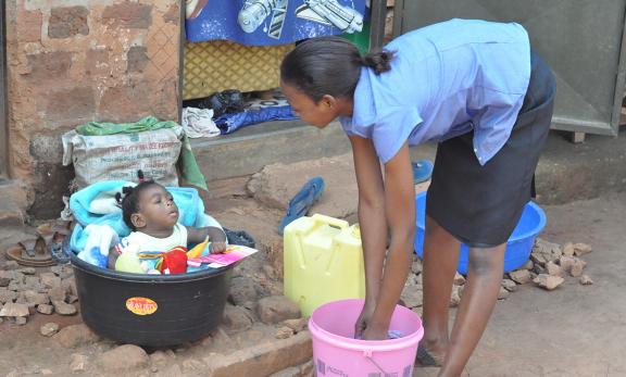 Women washing clothes while her baby looks on