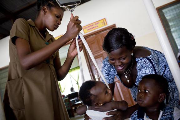 A nurse weighs baby held by its mother at a clinic in Accra, Ghana