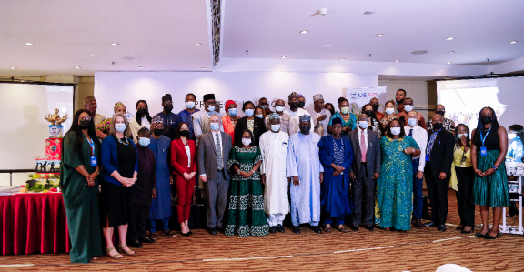 A large group of people wearing face coverings and colorful clothing stand together to get their picture taken.