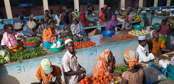 Shoppers buying produce in a solar powered market in Tanzania.