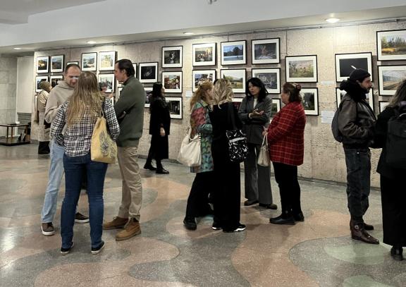 small groups of people gather to view the photo exhibit