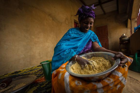 A woman prepares grains for consumption. 