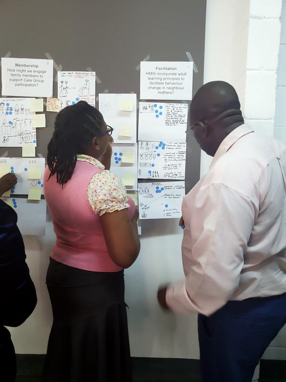 Photo of a woman and man looking at important looking information on a flow chart on the wall