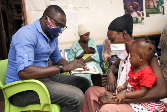 A Ghanaian health worker is counseling a mother and her child.