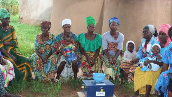 Members of a village savings and loans association group listen to a facilitator discuss effective breastfeeding practices