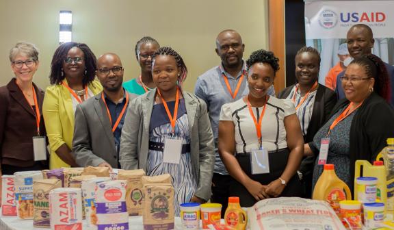 Staff of USAID Advancing Nutrition, Uganda pausing the gallery exhibition of some of the fortified food brands during the USAID Advancing Nutrition close-out dissemination event.