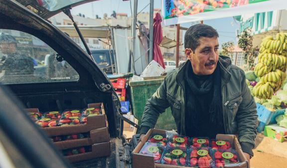 Photo of a man taking strawberries out of his vehicle and getting them ready to sell at a outdoor market.