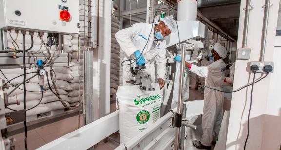 Photo of a man in a factory, filling a bag of processed flour.