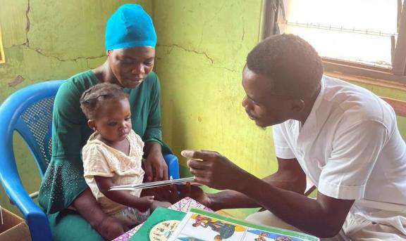 Photo of community health work counsels a mother and a baby
