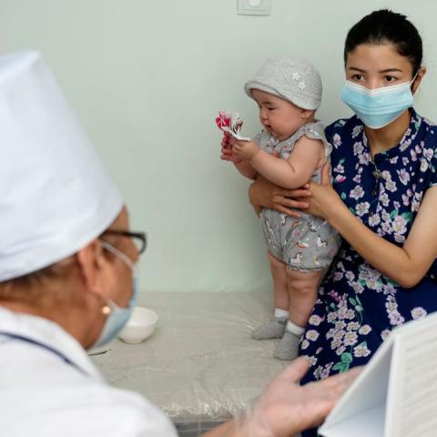 A mother holds her child while receiving health counseling at a health center in the Kyrgyz Republic