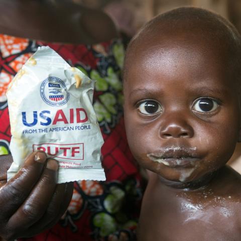 Photo of a small child being fed a "Ready to Use Therapeutic Food (RUTF)".