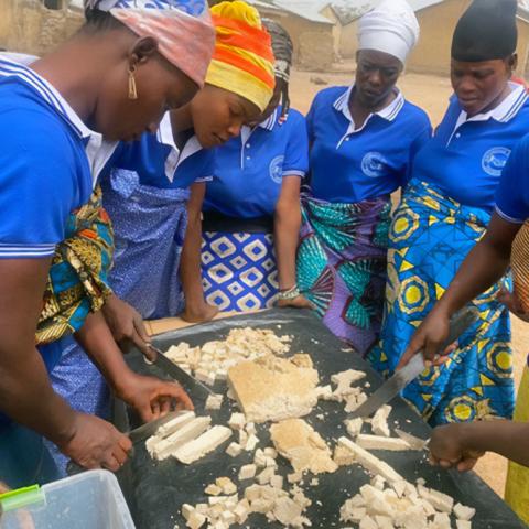 Village Savings and Loans Association /Mother to Mother Support Groups(VSLA/MTMSGs) in a cooking demonstration of the preparation of soya meal outdoors.