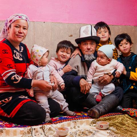 Family photo of two adults and five young children of various ages in traditional garb.
