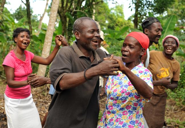 Photo showing five people dancing outside, with smiles on their faces.