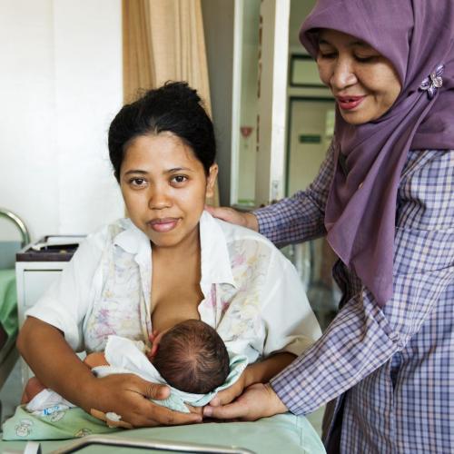 a midwife supports a new mother to breastfeed