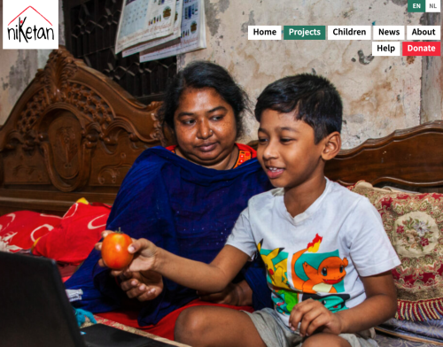 Photo of a mother and son sitting on the floor, the son is on a laptop and holding a piece of fruit in his hand.